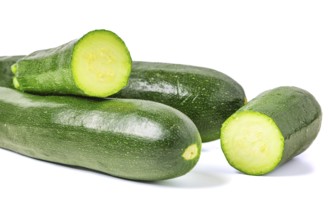 Courgettes (Cucurbita pepo), whole and cut, on white