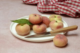 Peach, flat peaches in peel with knife