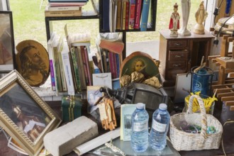 Religious statues, books and paintings for sale inside second hand goods and chattels store,