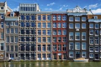 Row of typical houses and boat on Amsterdam canal Damrak with reflection. Amsterdam, Netherlands