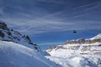 View of a ski resort piste with people skiing in Dolomites in Italy with cable car ski lift. Ski