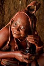 Traditionally dressed Himba woman in her hut, applying perfume, Purros Traditional Village, Purros,