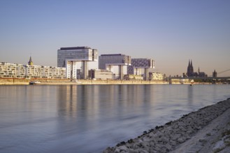 Crane houses in the Rheinau harbour and Cologne Cathedral seen across the Rhine from the bollard