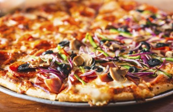 Close up of supreme pizza with olives on wooden table. Delicious Supreme Pizza and pepperoni on