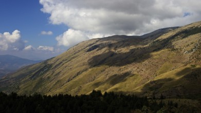 Hills, mottled green and yellow, light and shade, grey-white clouds, Madonie National Park, autumn,