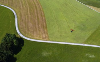 Drone view of a tractor turning hay in the field, Flachgau, Land Salzurg, Austria, Europe