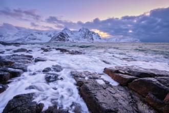 Beach of Norwegian sea on rocky coast in fjord on sunset in winter. Vareid beach, Lofoten islands,