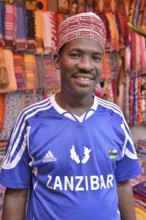 Clothing merchant wearing a football jersey of the Zanzibar Heroes, Stone Town, Zanzibar City,