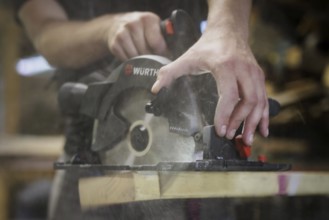 A man cuts wood with a hand-held circular saw. Berlin, 14.08.2024