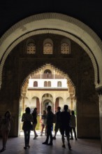 View through a gate, arabesque Moorish architecture, silhouette of tourists, Nasrid Palaces,