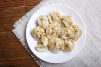 Dumplings on a linen tablecloth on a brown wooden background. top view, flat lay