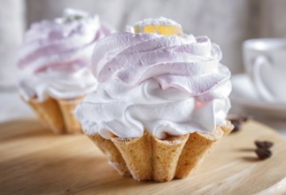 Cakes with whipped egg cream on wooden board, selective focus, close up