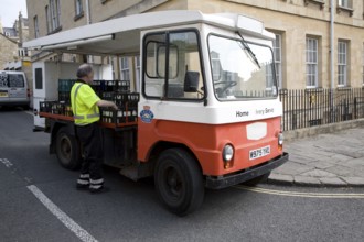 Milkman and traditional milk float home delivery service vehicle, Bath, Somerset, England, UK