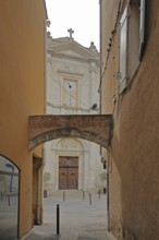 View baroque church Notre-Dames-des-Angers from narrow alley with archway, view through, narrow,