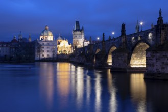 Charles Bridge with the Old Town Bridge Tower and the Church of the Holy Cross at the blue hour,