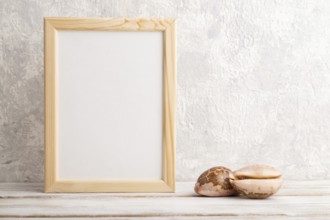 White wooden frame mockup with seashells on gray concrete background. Blank, vertical orientation,