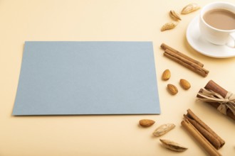 Composition with gray paper sheet, almonds, cinnamon and cup of coffee. mockup on orange background