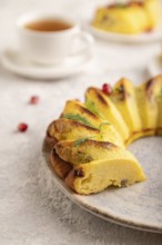 Cheesecake with cup of green tea on gray concrete background and orange linen textile. side view,