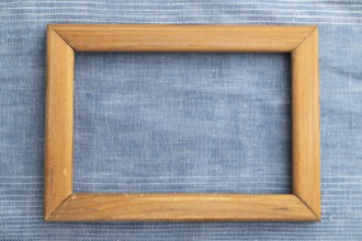 Wooden frame on smooth blue linen tissue. Top view, flat lay, natural textile background and