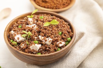 Quinoa porridge with green pea and chicken in wooden bowl on a white wooden background and linen