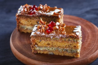 A piece of cake with caramel cream and poppy seeds on a wooden kitchen board. close up, selective