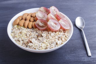 A plate with muesli, almonds, pink grapes on a black wooden background. close up