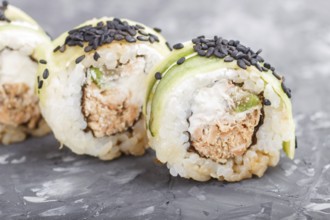 Japanese maki sushi rolls with tuna, cucumber, black sesame, cheese on black concrete background.