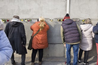 Visitors look through a gap in the Wall at the central commemorative event at the Berlin Wall