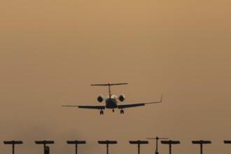 Gulfstream jet passenger aircraft on approach to land at sunset over landing lights, London