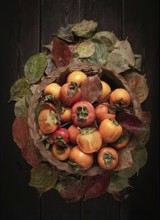 Fresh persimmon in a basket, with leaves, top view, no people