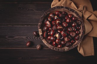 Roasted chestnuts, in a wooden plate, top view, homemade, no people