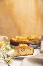 Orange cake and a cup of coffee on a white wooden background and linen textile. Side view, copy