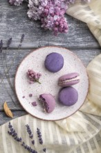 Purple macarons or macaroons cakes with cup of coffee on a gray wooden background and white linen