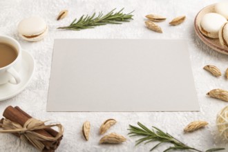 Gray paper sheet mockup with cup of coffee, almonds and macaroons on gray concrete background.