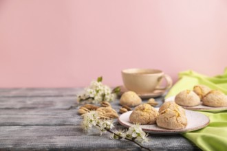 Almond cookies and a cup of coffee on a gray and pink background and green linen textile. Side