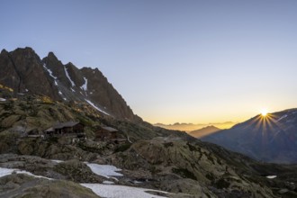 Morning atmosphere with sun star, mountain landscape at sunrise, mountain hut Refuge du Lac Blanc,