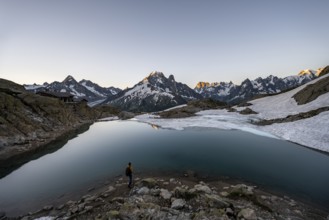 Tourist at a mountain lake in the morning, mountain landscape at sunrise, Lac Blanc, mountain peak,