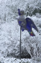 Blue Ulm sparrow with hoarfrost, ice and snow in winter, iced, sculpture, landmark, bird figure,