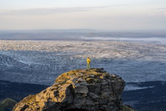 Young man, tourist in front of impressive glacier, in evening light, landscape with mountains and