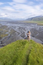 Hiker, Young woman on a hill, view over alluvial land, meandering river, Dímonarhellir, Suðurland,