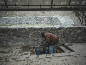 A man fills drinking water at a public well. In the northern and eastern neighbourhoods of Kharkiv,