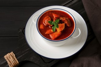 Stew with potatoes, in tomato sauce, with spices and herbs, close-up, no people, on a black