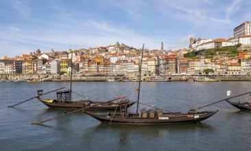 Old boats line the Douro River, with the charming Ribeira district in the background, Porto,