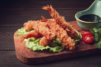 Fried shrimp, peeled in tempura, soy sauce, close-up, on a wooden board