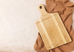 Cutting board, beige, unpainted, with a kitchen towel, on a beige background, top view