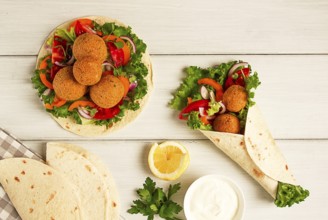 Tortillas, wrapped falafel balls, with fresh vegetables, vegetarian healthy food, on a wooden white