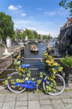 Sint Antoniesluis, on the Oudeschans canal, bicycle decorated with sunflowers, canal cruise boat,