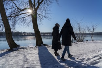 Winter in the Ruhr area, Lake Baldeney, snow-covered, partly frozen lake, walkers on the lakeside