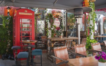 Cosy outdoor café with red British telephone box and lush decoration of plants and flowers,