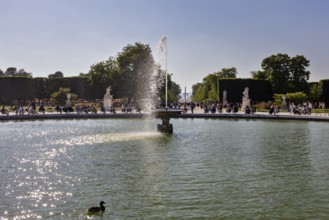 A large fountain with ducks and surrounding statues, surrounded by people in a park, Paris